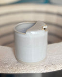 Rustic beige ceramic to-go cup on a kiln edge