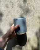 Hand holding a handmade blue ceramic to-go cup 